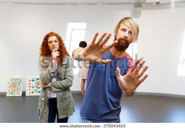 Young artists in gallery hanging painting on walls