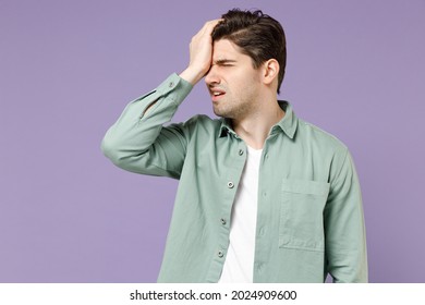 Young ashamed mistaken sad man 20s wearing casual mint shirt white t-shirt putting hand on face do facepalm epic fail gesture isolated on purple background studio portrait. People lifestyle concept.