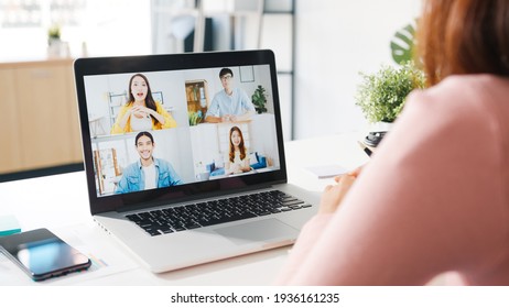 Young Asia businesswoman using laptop talk to colleague about plan in video call meeting while work from home at living room. Self-isolation, social distancing, quarantine for corona virus prevention. - Shutterstock ID 1936161235