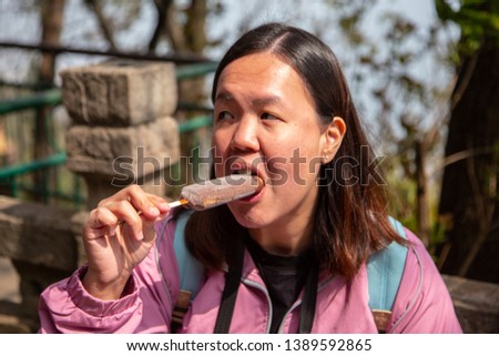 A Young Asia Chinese Lady happy eating Ice Cream.