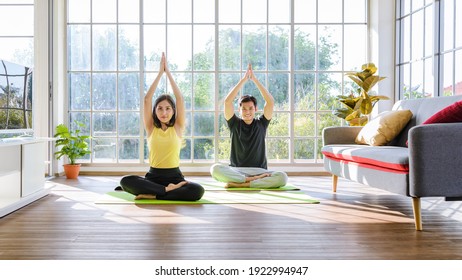 Young Asia couple practicing yoga lesson, breathing and meditating together in living room at home. healthy lifestyle concept - Powered by Shutterstock