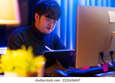 Young Asia Freelance Creative Designer Programer Focus Working Hand Using Pen With Tablet Thinking Concentrate Working Late At Home Overtime At Night Low Light Ambient In Living Room With City Bokeh