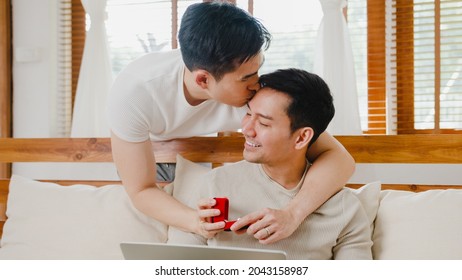 Young Asia Gay Couple Propose At Modern Home, LGBTQ Men Happy Smiling Have Romantic Time While Proposing And Marriage Surprise Wear Wedding Ring In Living Room At House. Anniversary Romantic Concept.