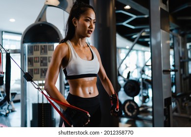 Young Asia lady exercise doing exercise-machine Cable Crossover fat burning workout in fitness class. Athlete with six pack, Sportswoman recreational activity, functional training, healthy lifestyle.