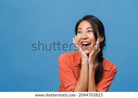 Young Asia lady feel happiness with positive expression, joyful surprise funky, dressed in casual cloth isolated on blue background. Happy adorable glad woman rejoices success. Facial expression.