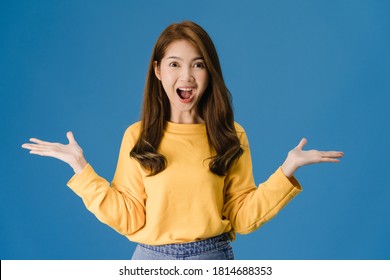 Young Asia lady feeling happiness with positive expression, joyful surprise funky, dressed in casual cloth and looking at camera isolated on blue background. Happy adorable glad woman rejoices success