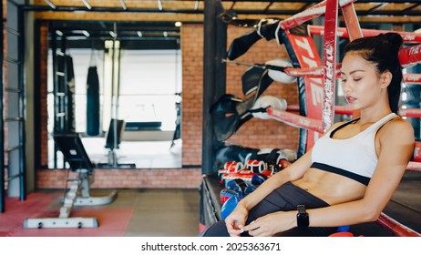 Young Asia lady kickboxing exercise workout feels tired after sport training on boxing ring in gym fitness class. Sportswoman recreational activity, functional training, healthy lifestyle concept.