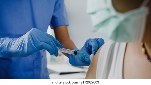 Young Asia Lady Nurse Giving Covid-19 Or Flu Antivirus Vaccine Shot To Teenage Girl Patient Wear Face Mask Protection From Virus Disease At Health Clinic Or Hospital Office. Close Up Or Closeup Shot.