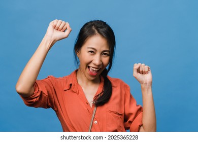 Young Asia lady with positive expression, joyful and exciting, dressed in casual cloth and look at camera over blue background. Happy adorable glad woman rejoices success. Facial expression concept.