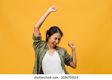 Junge Asienfrau mit positivem Ausdruck, fröhlich und aufregend, gekleidet in lockerem Stoff auf gelbem Hintergrund mit leerem Raum. Fröhliche, verehrte Frau freut sich über den Erfolg. Gesichtsausdruck-Konzept.