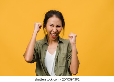 Young Asia lady with positive expression, joyful and exciting, dressed in casual cloth and look at camera over yellow background. Happy adorable glad woman rejoices success. Facial expression concept.