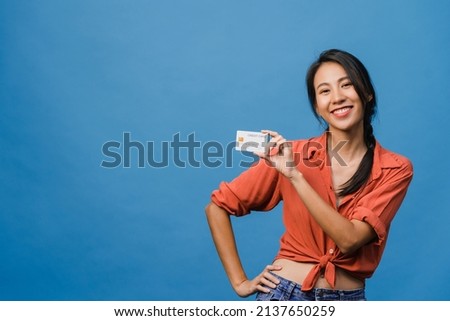 Young Asia lady show credit bank card with positive expression, smiles broadly, dressed in casual clothing feeling happiness and stand isolated on blue background. Facial expression concept.