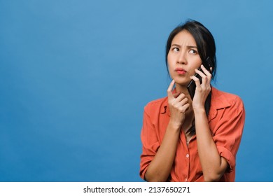 Young Asia Lady Talk By Phone With Negative Expression, Excited Screaming, Cry Emotional Angry In Casual Cloth And Stand Isolated On Blue Background With Blank Copy Space. Facial Expression Concept.