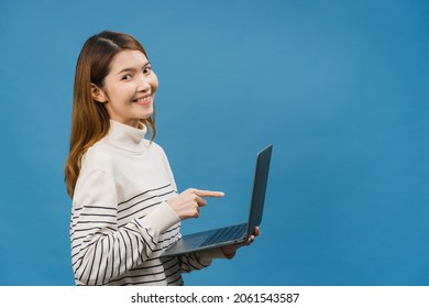 Young Asia lady using laptop with positive expression, smiles broadly, dressed in casual clothing feeling happiness and stand isolated on blue background. Happy adorable glad woman rejoices success. - Shutterstock ID 2061543587