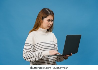 Young Asia Lady Using Laptop With Negative Expression, Excited Screaming, Cry Emotional Angry In Casual Cloth And Stand Isolated On Blue Background With Blank Copy Space. Facial Expression Concept.