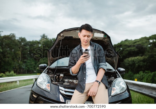 Young Asia man having trouble with his broken\
car,Using smart phone