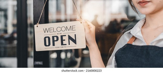 Young Asia manager girl changing a sign from closed to open sign on door cafe looking outside waiting for clients after lockdown. Owner small business, food and drink, business reopen again concept - Powered by Shutterstock