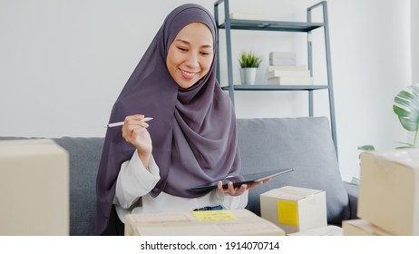 Young Asia muslim businesswoman check product purchase order on stock and save to tablet computer work at home office. Small business owner, online market delivery, lifestyle freelance concept. - Powered by Shutterstock