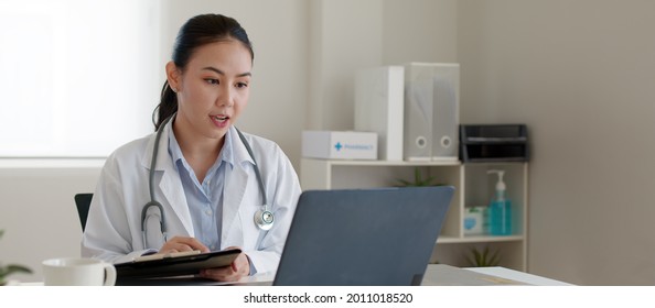Young asia people or female doctor live talk looking and speaking at laptop computer work in online clinic to help patient on digital telehealth telemedicine smart covid consult VoIP service app. - Powered by Shutterstock
