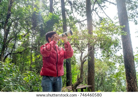 A young asia Scientists explore forests. hand holding camera. discovery concept,
Wildlife conservationist, Wildlife Photographer holding pro digital camera with telephoto lens