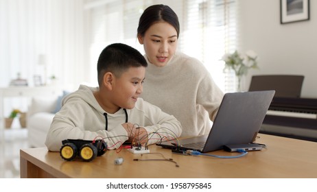 Young Asia Student Remotely Learn Online At Home With Parent In Coding Robot Car And Electronic Board Cable In STEM, STEAM, Mathematics Engineer Science Technology Computer Code In Robotics For Kids.