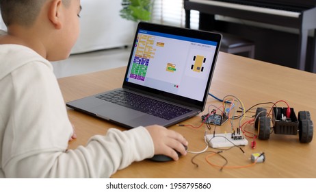 Young asia student remotely learn online at home in coding robot car and electronic board cable in STEM, STEAM, mathematics engineering science technology computer code in robotics for kids concept.