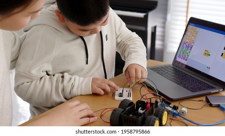 Young asia student remotely learn online at home with parent in coding robot car and electronic board cable in STEM, STEAM, mathematics engineer science technology computer code in robotics for kids. - Powered by Shutterstock