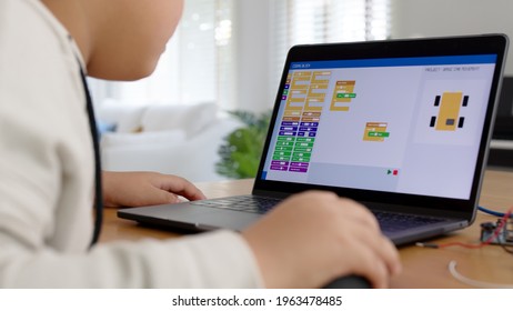 Young Asia Student Remotely Learn Online At Home In Coding Robot Car And Electronic Board Cable In STEM, STEAM, Mathematics Engineering Science Technology Computer Code In Robotics For Kids Concept.