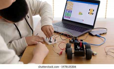 Young asia student remotely learn online at home with parent in coding robot car and electronic board cable in STEM, STEAM, mathematics engineer science technology computer code in robotics for kids.