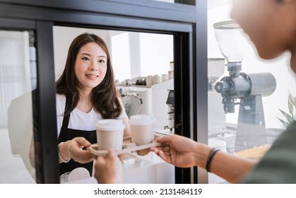 Young asia woman hands gives paper coffee cup on slide glass window. Take away delivery concept. Asian woman barista. Sustainable cup waitress and buyer hold coffee, eco recycle environment friendly. - Powered by Shutterstock