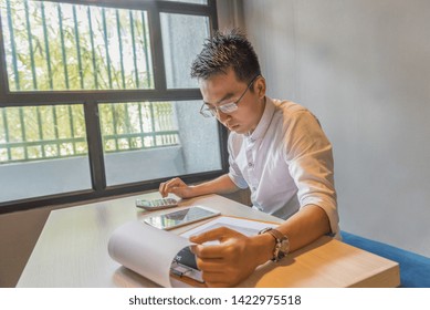 Young Asian Accountant Working On Financial Document And Calculator