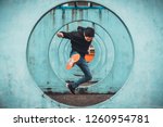 Young Asian active man jumping and kicking action, circle looping wall background. Extreme sport activity, parkour outdoor free running, or healthy lifestyle concept