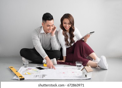 Young Asian Adult Couple Sitting On Flor Planning New Home Design.