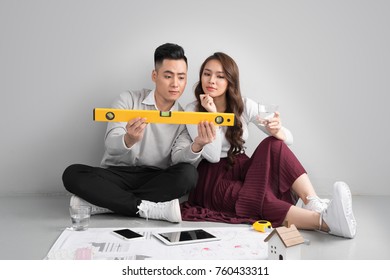 Young Asian Adult Couple Sitting On Flor Planning New Home Design.