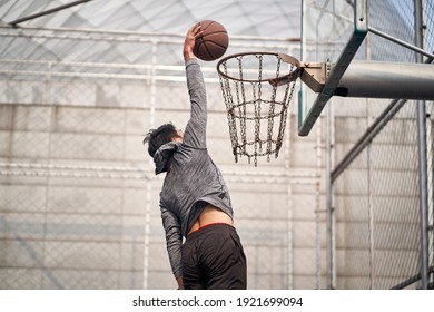 young asian adult man basketball player attempting a dunk on outdoor court - Powered by Shutterstock