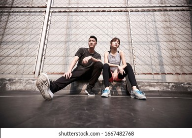 Young Asian Adult Man And Woman Resting After Exercise With Cool Attitude