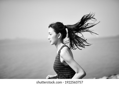 Young Asian Adult Woman Running Jogging Outdoors By The Sea, Side View, Black And White