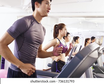 Young Asian Adult Working Out On Treadmill, Focus On The Girl In The Middle.