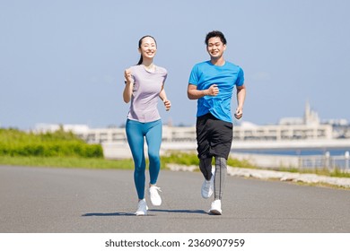 Young Asian adults jogging outdoors - Powered by Shutterstock