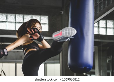 Young asian athlete woman with boxing gloves doing kick boxing training in sport gym - Powered by Shutterstock