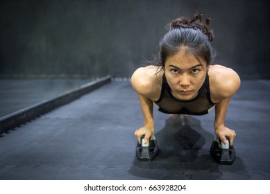 Young Asian Athlete Woman Doing Push Up With Push-up Bars On The Floor. Sport And Training In Fitness Gym Concepts