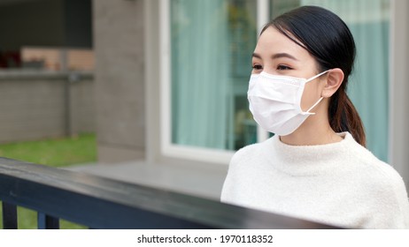 Young Asian Attractive Beautiful Woman Wear Face Mask In Front Of House Talk Smile Positive With Copy Space Social Distance In Covid Coronavirus At Home. Conversation In Person At Safe Distance.