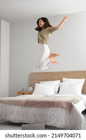 Young Asian Barefoot Woman Jumping On Bed At Home