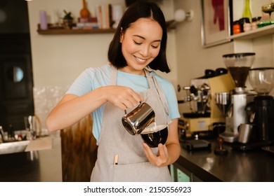 Young Asian Barista Woman Wearing Apron Smiling While Making Coffee In Cafe