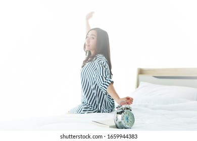 Young Asian Beautiful Cute Love Woman Sitting And  Stretching On Bed After Wake Up And Alarm Clock Ringing Before Take The Shower And Go To Study In University. Bangkok Thailand South East Asia