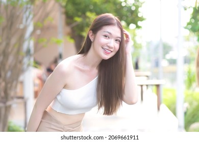 Young Asian Beautiful Woman With Good Skin In Cream Shirt Standing Smiling Happily On Blurred Background.