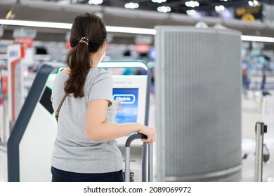 Young Asian beautiful woman tourist try to use automatic self check-in kiosk in the airport, Asian tourist using self check in machine.