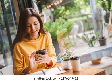 Young Asian Beautiful Woman Using Smart Phone For Business, Online Shopping, Transfer Money, Financial, Internet Banking. In Coffee Shop Cafe Over Blurred Background.