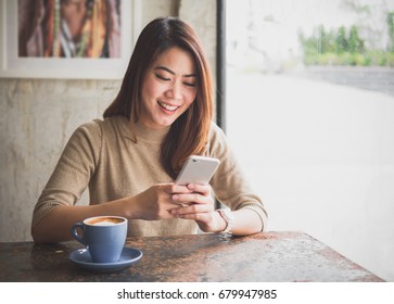 Young Asian beautiful woman using smart phone for business, online shopping, transfer money, financial, internet banking. in coffee shop cafe over blurred background.