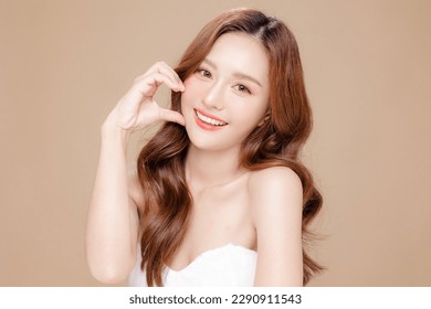Young Asian beauty woman curly long hair with korean makeup style touch her face and perfect skin on isolated beige background. Facial treatment, Cosmetology, plastic surgery. - Shutterstock ID 2290911543